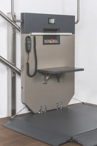 Hublift mit ausgeklappter Plattform neben einer Treppe, daneben der Handlauf