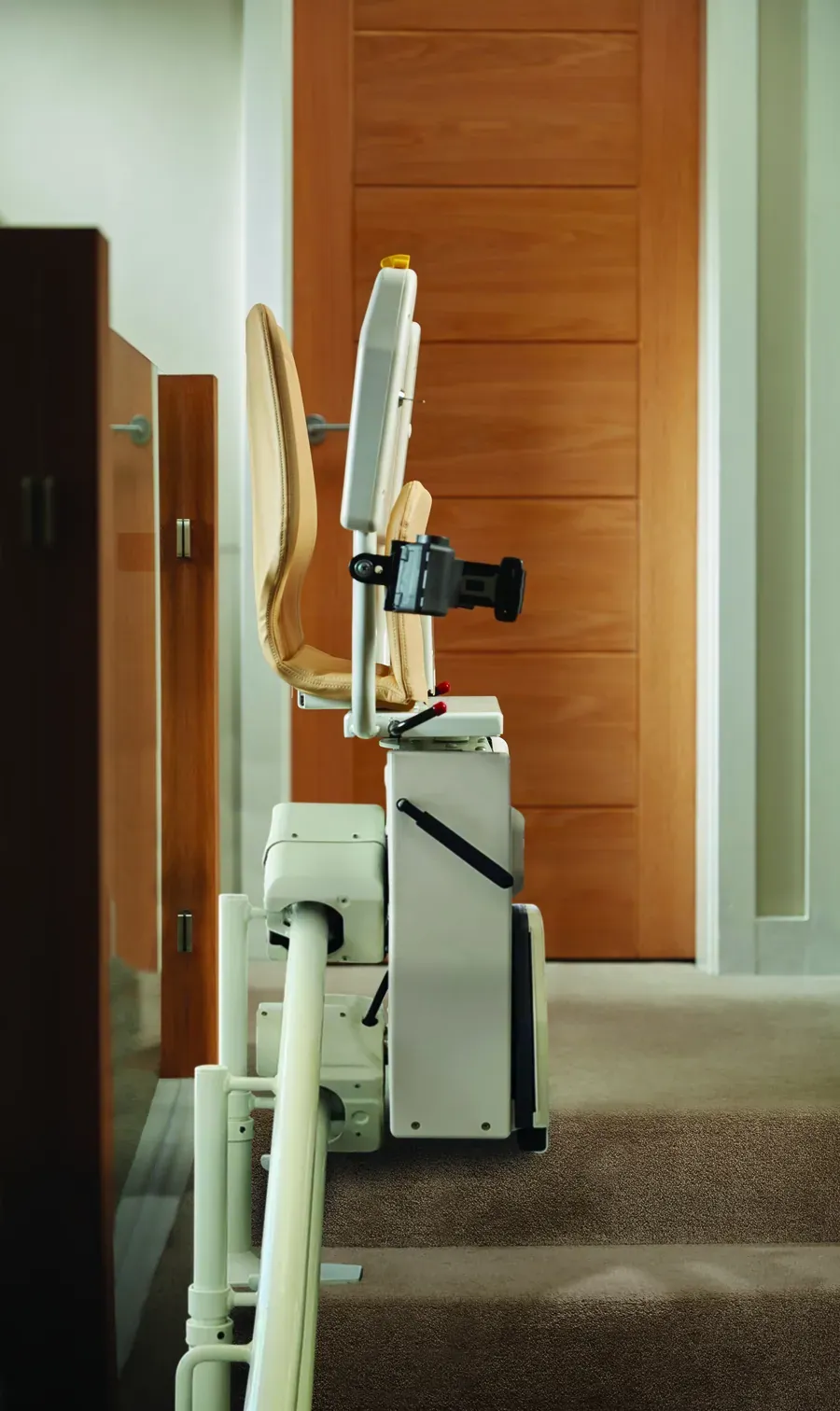 Sitzlift in Parkposition am oberen Treppenabsatz, Sitz und Fußstütze hochgeklappt, die Stufen bleiben frei begehbar